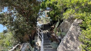 Eine steinerne Treppe, umgeben von großen Felsen und Kakteen, die nach oben führt.