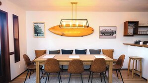 A dining area with a wooden table, six chairs, a patterned rug, and wall art depicting British Columbia. - Secluded Oceanfront - Upstairs (Tofino)
