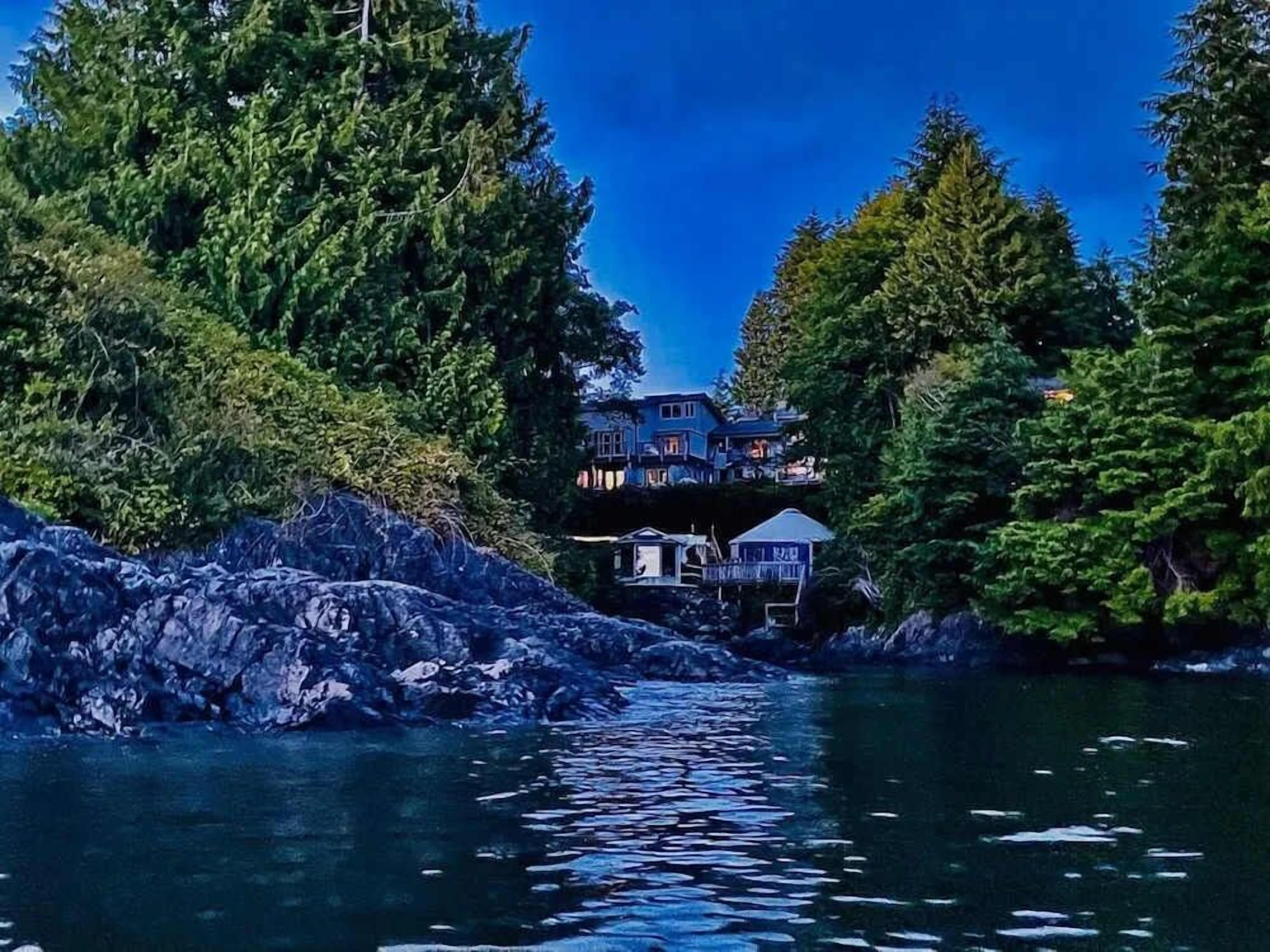 Ein Küstenanwesen mit einem Haus, umgeben von dichtem Wald.