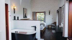 A modern bathroom with a freestanding bathtub, a vanity, and a bed with a view. - Secluded Oceanfront - Upstairs (Tofino)