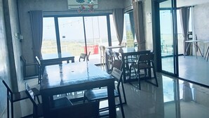 A spacious dining area with a large table and chairs, large windows with curtains, and a view of the cityscape.