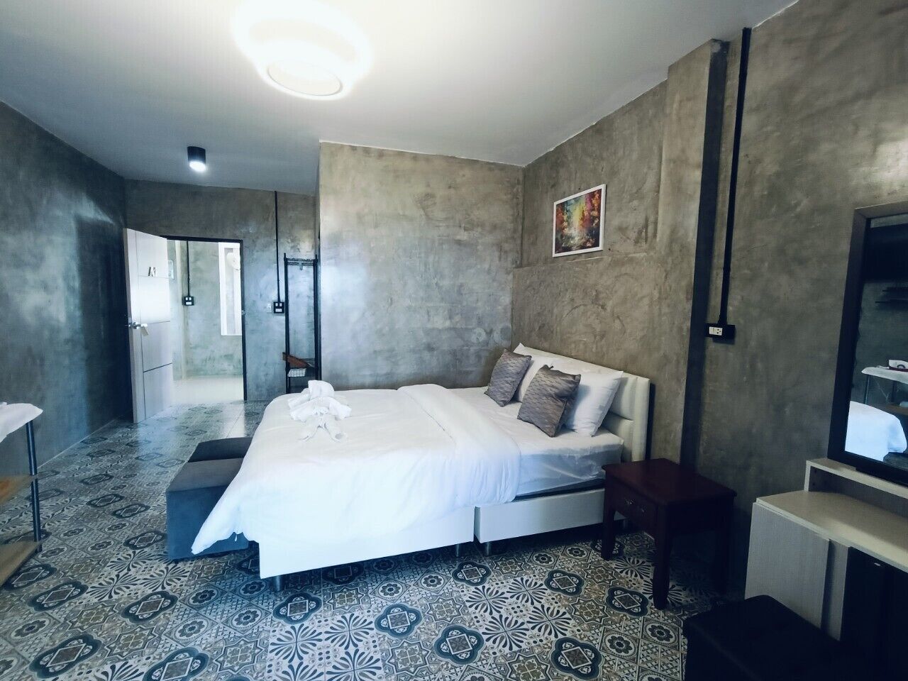 A modern bedroom with a large bed, a bedside table, a TV, and a mirror.