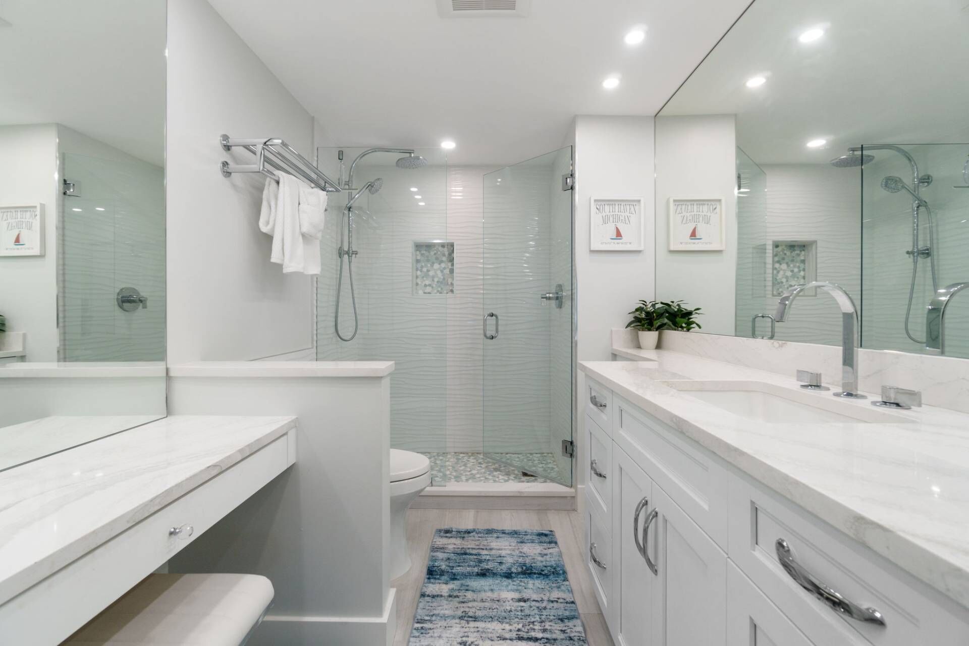 A modern bathroom with a glass-enclosed shower, a white toilet, and a vanity with a large mirror.