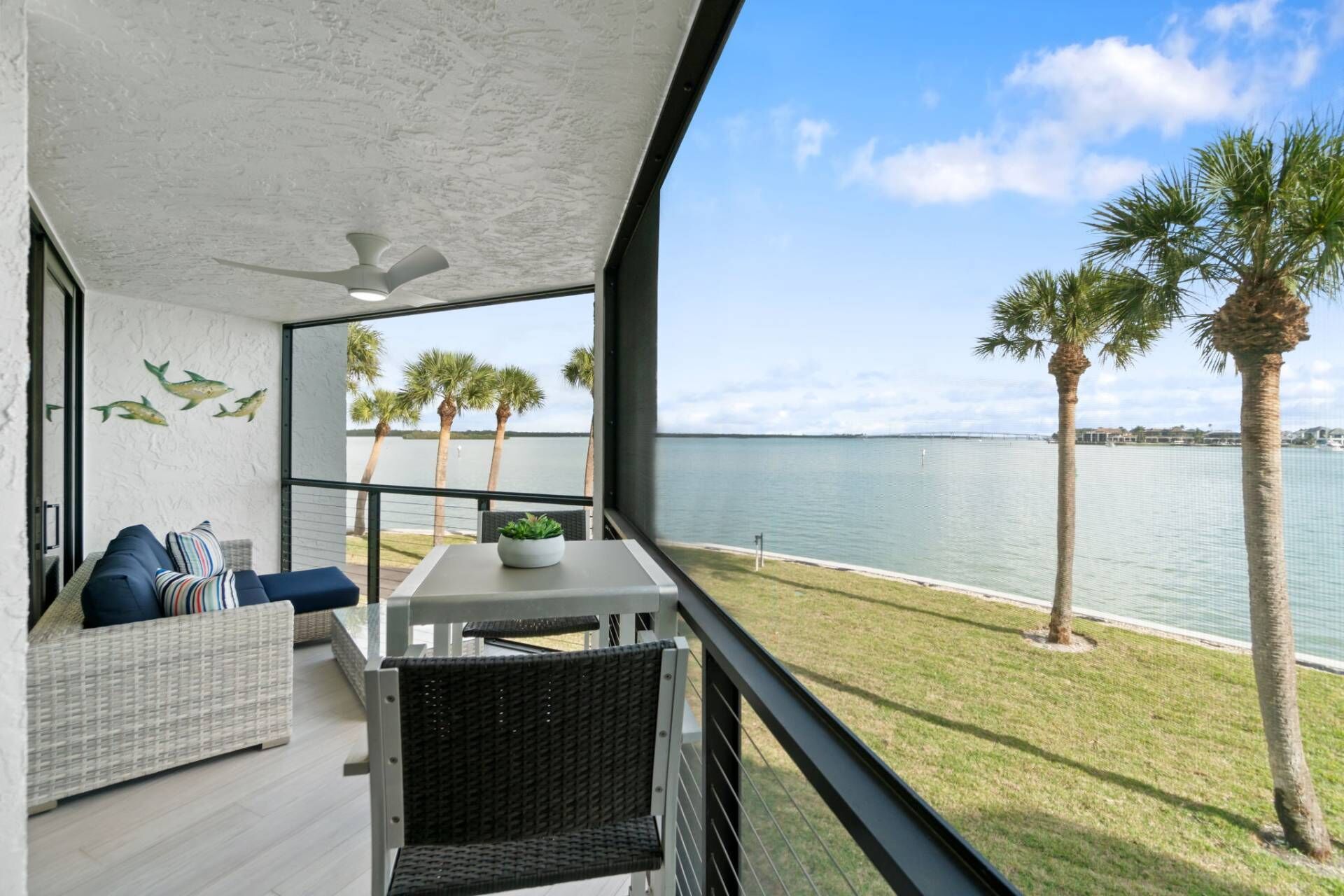 A balcony with a view of the water, a sofa, and a table with a plant.