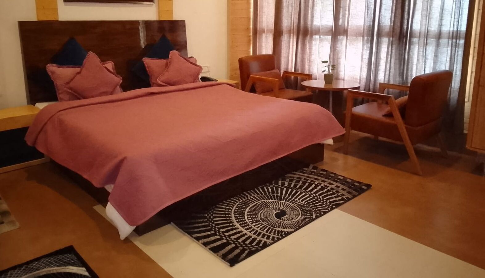 A bedroom with a bed, a small round table, and two chairs.