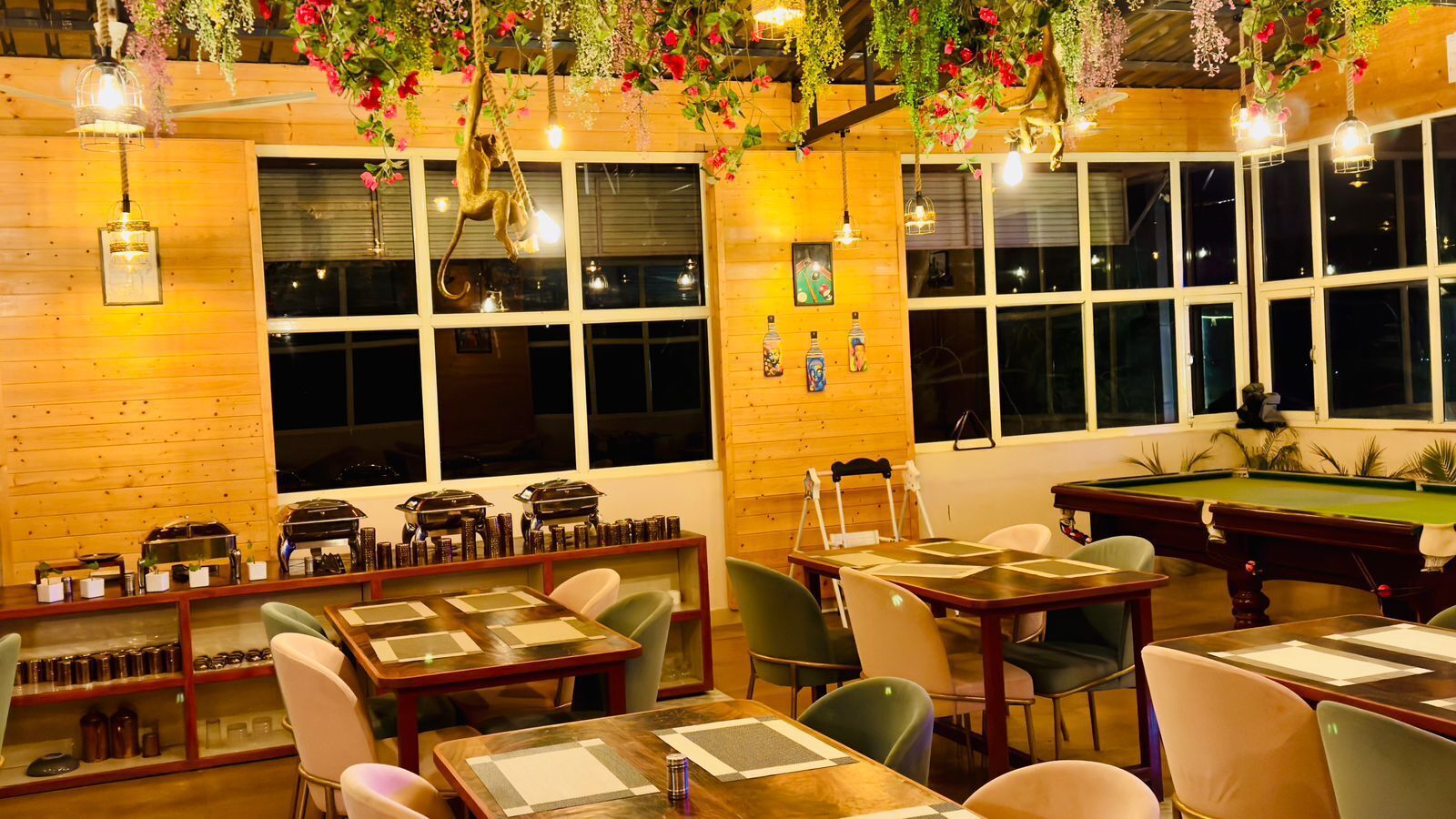 Ein gemütliches Restaurant mit Holzwänden, einem Billardtisch und blumengeschmückten Girlanden.