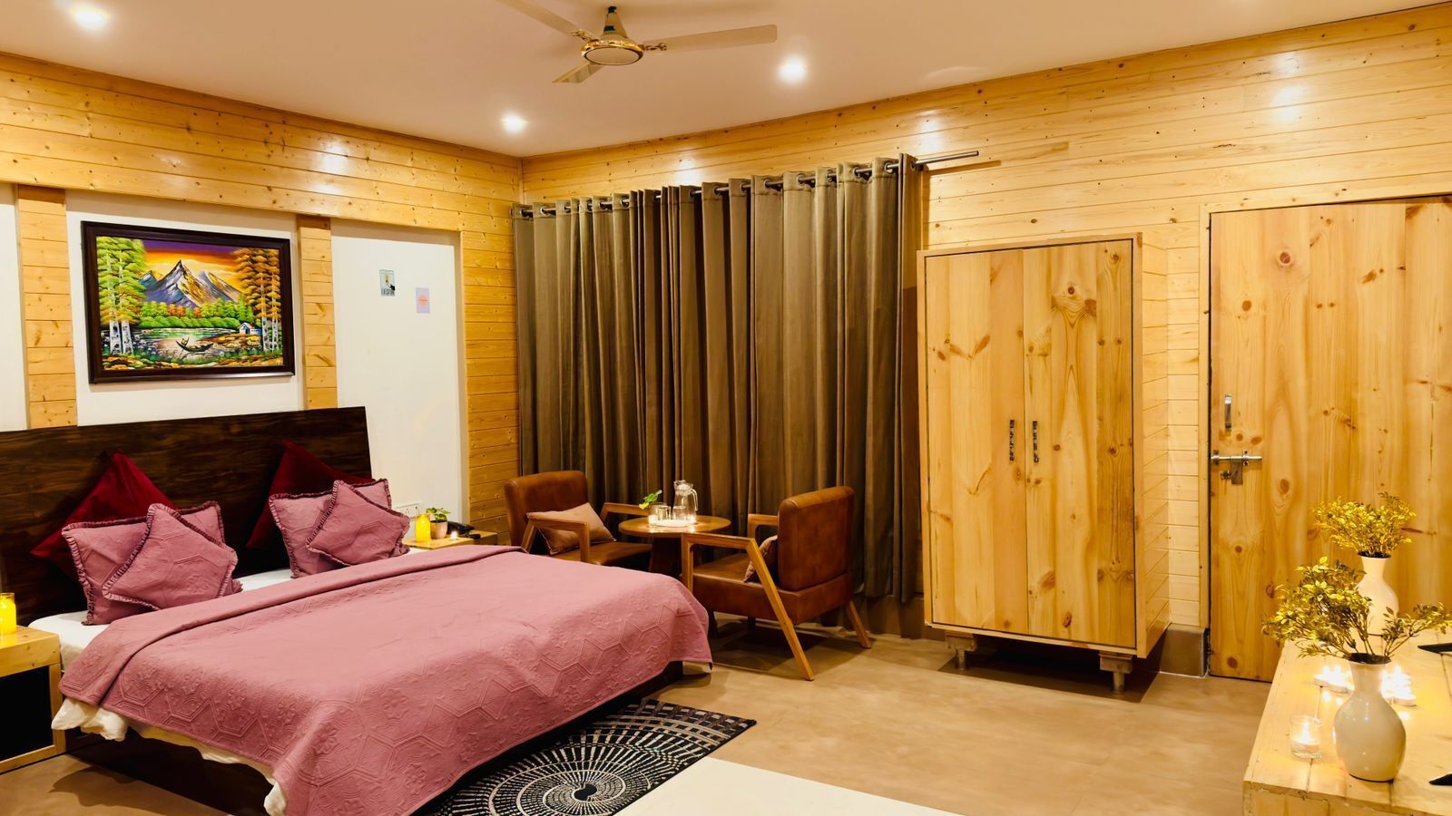 Un dormitorio con una cama, dos sillas, una mesa, un armario y un cuadro en la pared.