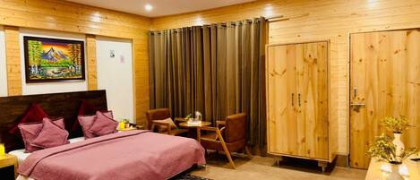 Un dormitorio con una cama, dos sillas, una mesa, un armario y un cuadro en la pared.