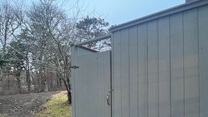 A metal utility shed with a door, located next to a building.