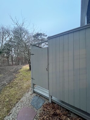 A metal utility shed with a door, located next to a building.
