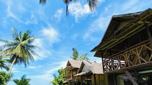 A beachfront property with wooden structures, a grassy lawn, and palm trees. - Ocam Ocam Casadyan Inn (Busuanga)