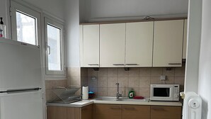 A kitchen with white cabinets, a Bosch refrigerator, a microwave, and a sink. - Pnyka Apartment 2 (Athens)