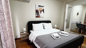 A bedroom with a bed, a bedside table with a lamp, a wall-mounted air conditioner, and a painting. - Pnyka Apartment 2 (Athens)