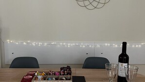 A dining table with a bottle of wine, two glasses, and a box of snacks. - Pnyka Apartment 2 (Athens)