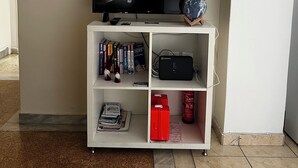 A white entertainment unit with a flat-screen TV, a decorative globe, and a Cosmote router. - Pnyka Apartment 2 (Athens)