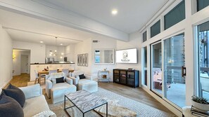 Amplia sala de estar con mesa de comedor, sofás, chimenea y un ventanal con vistas.
