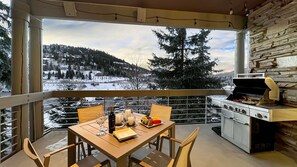 Een balkon met een tafel gedekt voor twee personen, een barbecue en een schilderachtig uitzicht op de bergen.