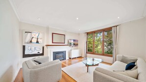 A modern living room with a fireplace, two sofas, a glass coffee table, and artwork on the walls.