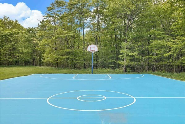 An outdoor basketball court surrounded by trees.