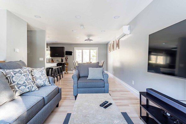 A modern living room with a grey sofa, a coffee table, and a flat-screen TV.