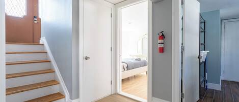 A staircase leading to a bedroom with a bed, a fire extinguisher, and a bathroom with a shower.