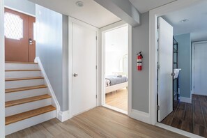 A staircase leading to a bedroom with a bed, a fire extinguisher, and a bathroom with a shower.