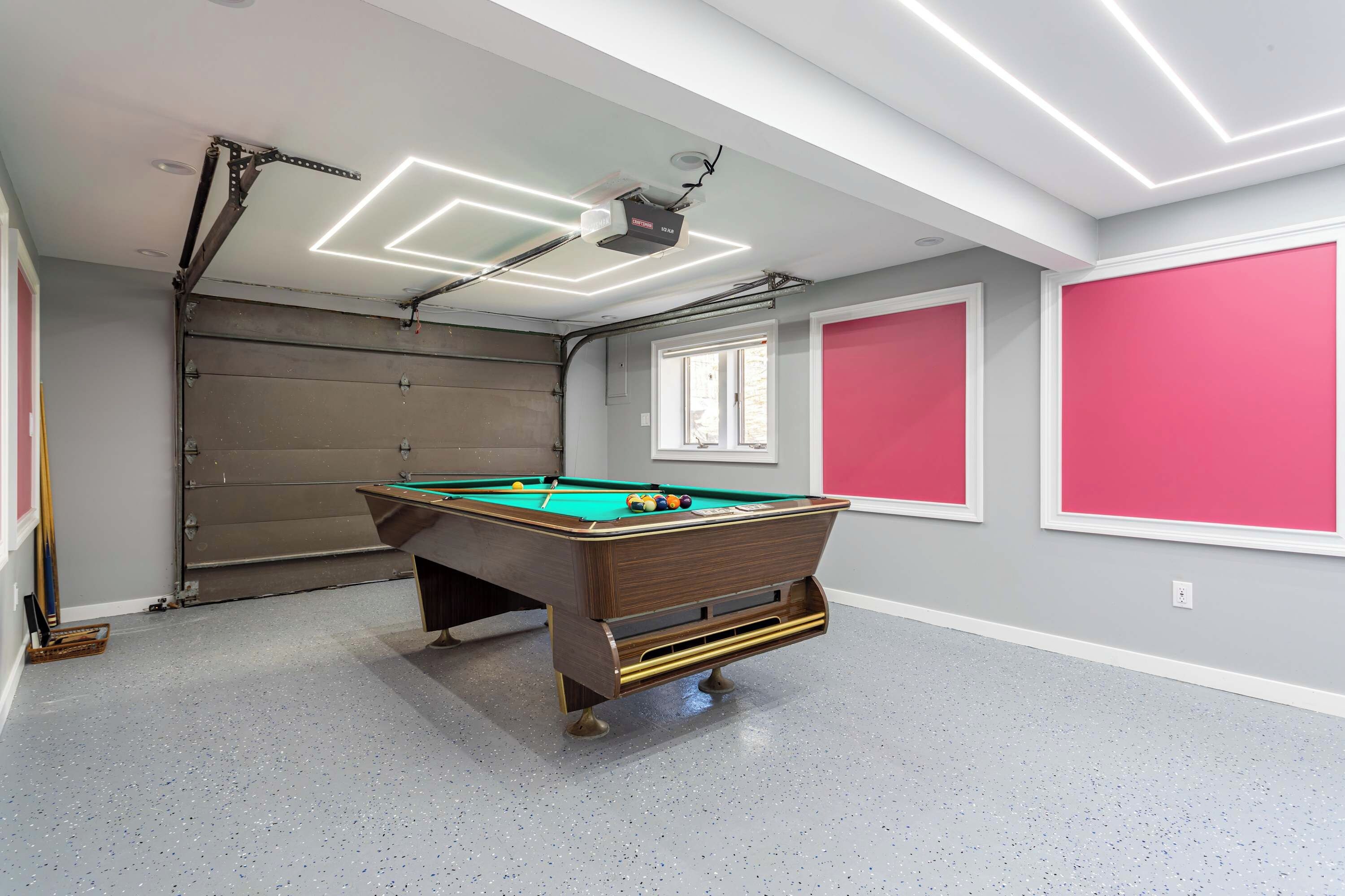 A pool table in a room with a grey floor, a window, and a door.