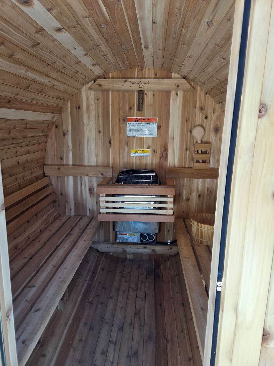 Eine Sauna mit Holzwänden und einer Sitzbank. An der Wand befinden sich Warnschilder.