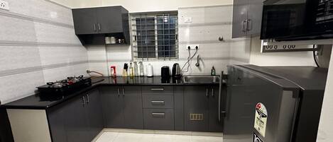 A modern kitchen with dark cabinetry, a stainless steel sink, and a built-in microwave.