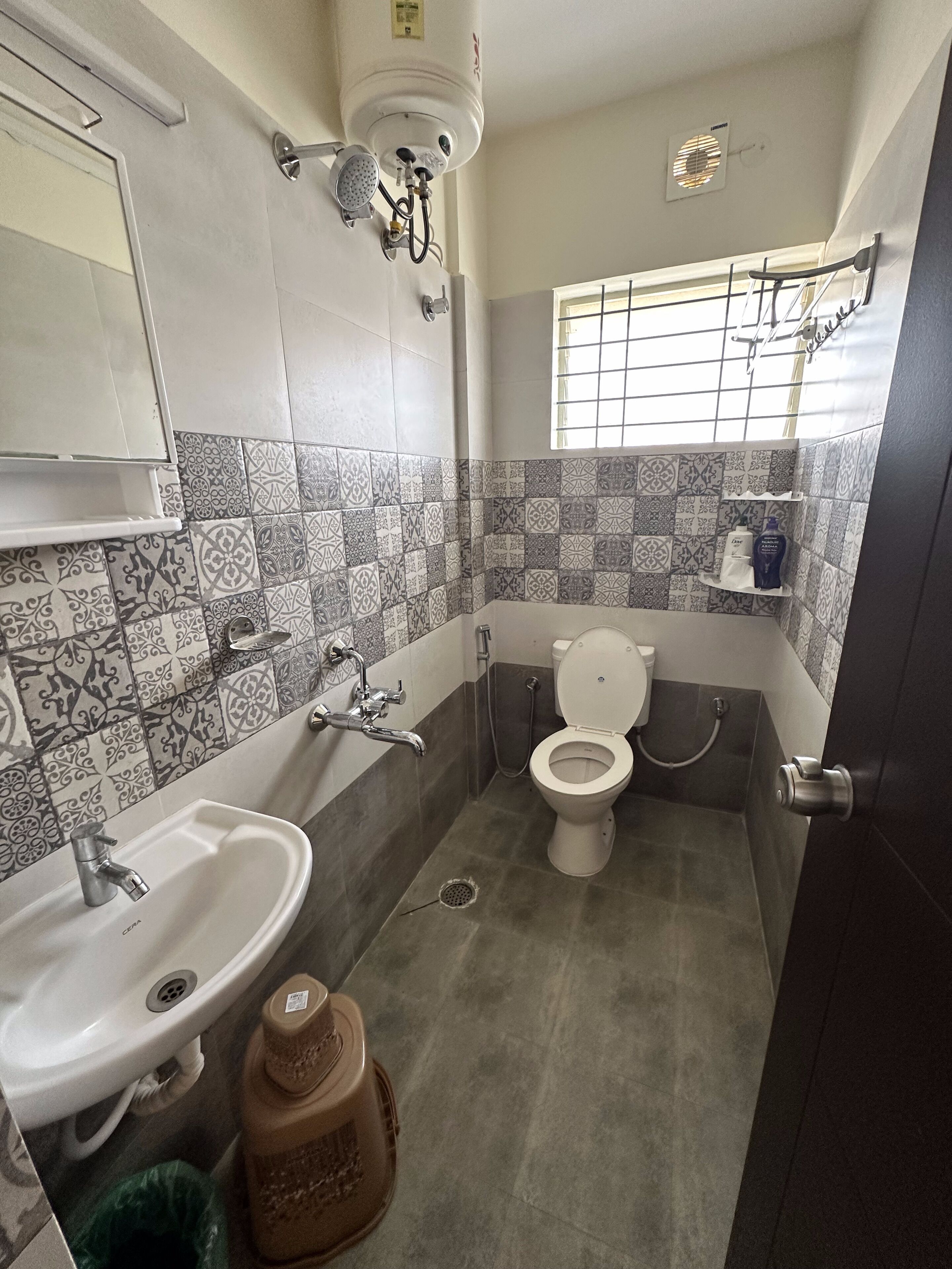 A bathroom with a sink, toilet, and shower. The walls are tiled with a patterned design.