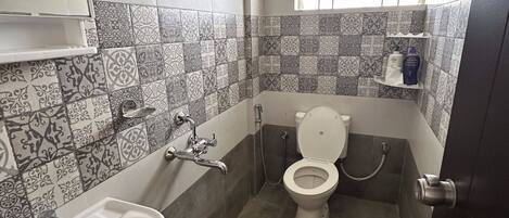 A bathroom with a sink, toilet, and shower. The walls are tiled with a patterned design.