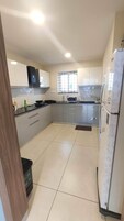 A modern kitchen with white cabinets, a black countertop, and a stainless steel refrigerator.