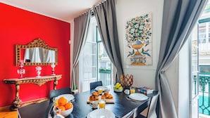 A dining area with a red wall, a large mirror, and a table set with plates, glasses, and a fruit bowl.