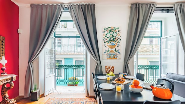 A dining area with a table set for breakfast, a decorative vase, and a view of the balcony.