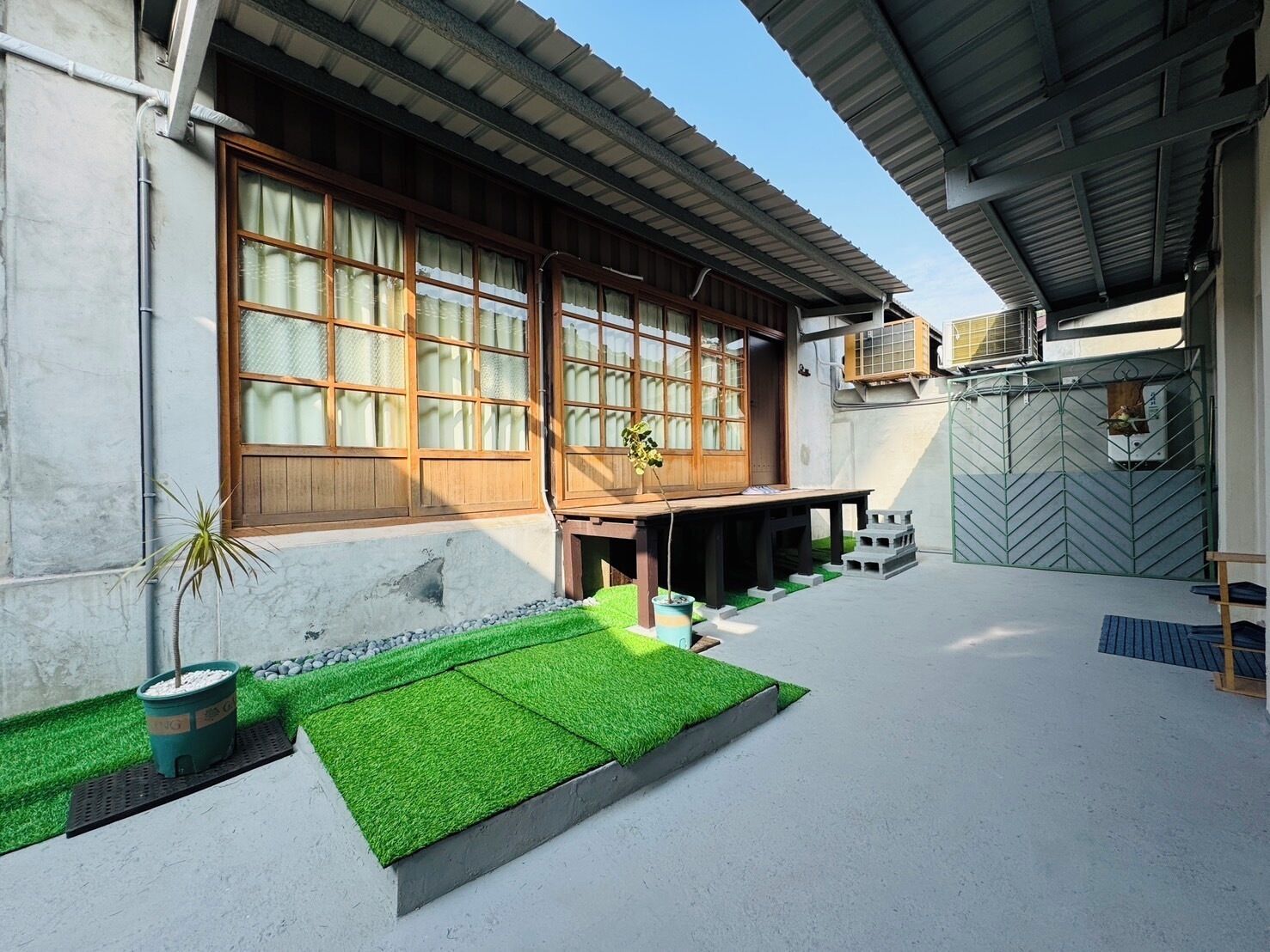 A modern house with a large wooden door, a small porch, and a concrete patio with artificial grass.