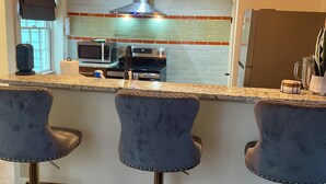 A modern kitchen with a central island, bar stools, and pendant lighting.