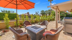 An outdoor patio with wicker furniture, a grill, and an orange umbrella. - Oasis in Hidden Palms! Pool, Spa, Pickle Ball, Gated Community (Palm Desert)
