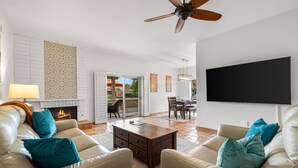 A living room with a fireplace, leather sofas, a coffee table, and a ceiling fan. - Oasis in Hidden Palms! Pool, Spa, Pickle Ball, Gated Community (Palm Desert)
