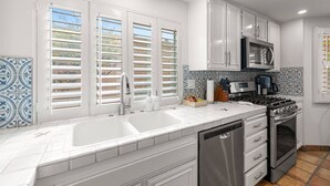 A modern kitchen with white cabinets, a stainless steel range, a dishwasher, and a microwave. - Oasis in Hidden Palms! Pool, Spa, Pickle Ball, Gated Community (Palm Desert)