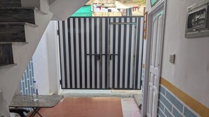 Un pasillo estrecho con un portón a rayas negras y blancas, suelo de baldosas y un banco.