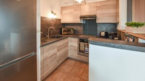 Eine moderne Küche mit Holzschränken, einem Edelstahlkühlschrank, einem Einbauofen und einer Mikrowelle.