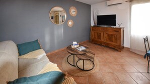 Ein Wohnzimmer mit einer Couch, zwei runden Couchtischen, einem Fernseher und einem Holzschrank.
