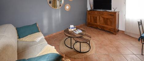 A living room with a sofa, two round coffee tables, a TV, and a wooden cabinet.