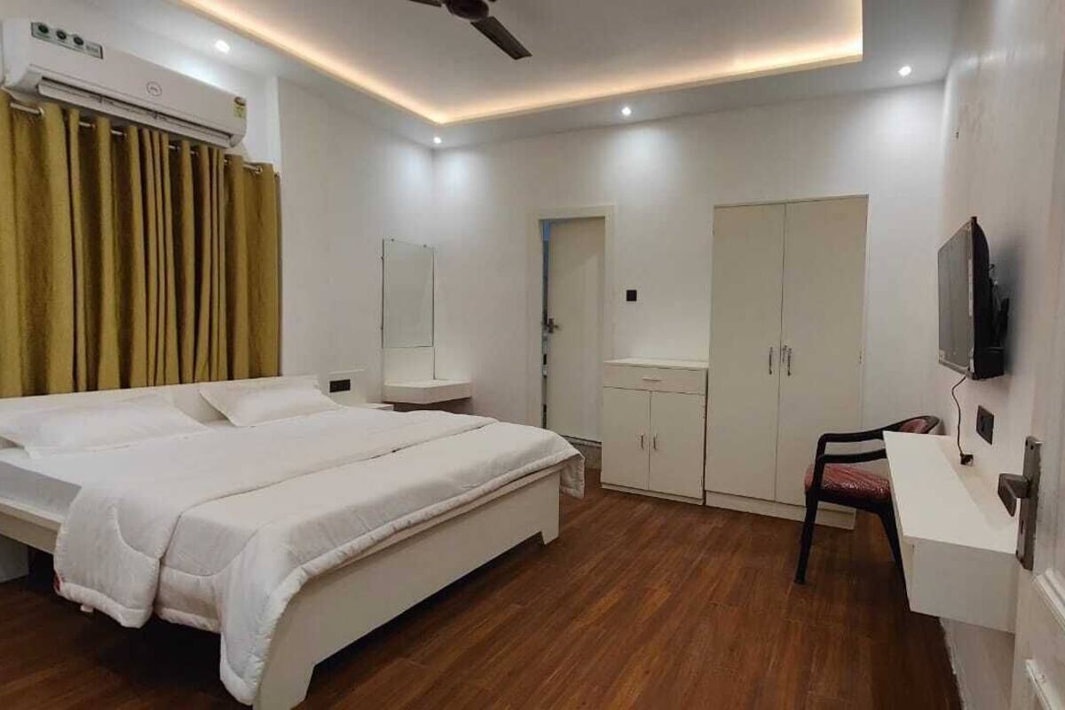 Ett hotellrum med två sängar, ett skrivbord, en garderob, en tv och en luftkonditioneringsanläggning.