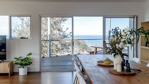 Una cocina moderna con ventanas amplias, una mesa de comedor de madera y una planta en maceta.