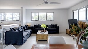 Una sala de estar moderna con un sofá modular, una mesa de centro y un televisor.