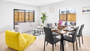 A modern living room with a dining area, a yellow bean bag, a grey sofa, and a dining table set for four.