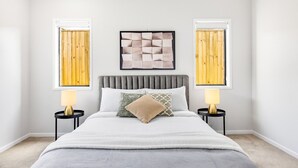 A bedroom with a large bed, two bedside tables, and a headboard.