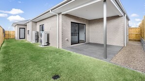 A modern house with a covered patio, a brick exterior, and a well-maintained lawn.