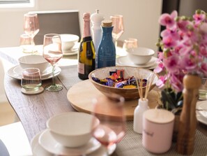 A dining table set with plates, glasses, a bottle, and a bowl of snacks.